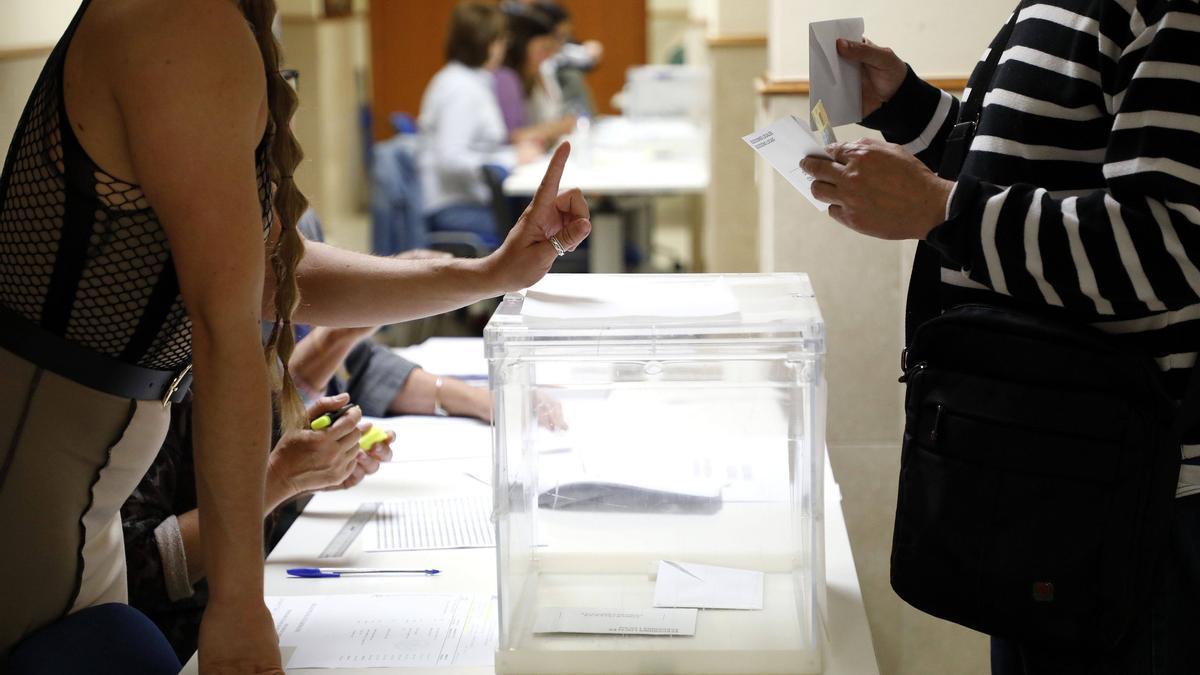 Una mujer prepara su papeleta e identificación para votar en la facultad de Derecho, en Santiago