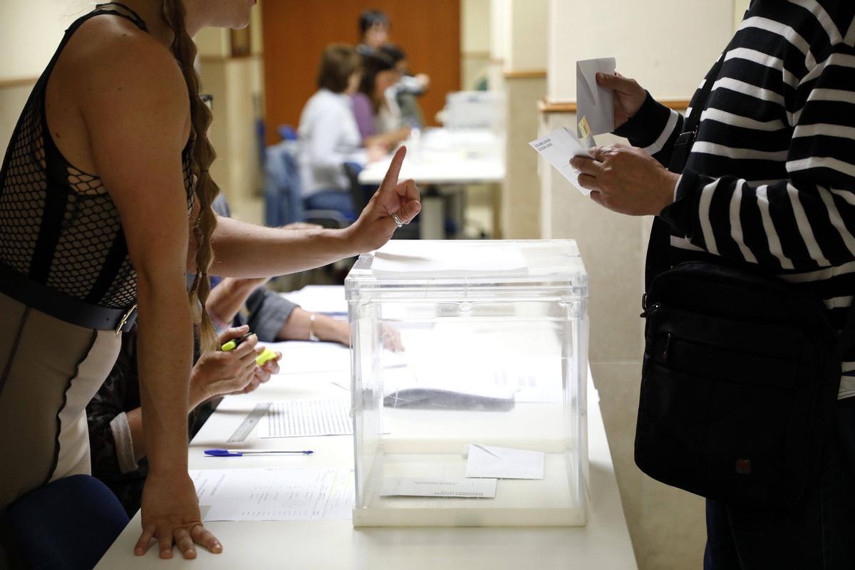 Una mujer prepara su papeleta e identificación para votar en la facultad de Derecho, en Santiago