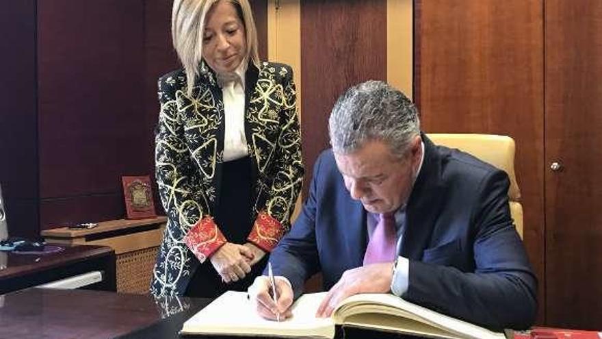 Amparo Antuña observa a Belarmino Feito firmando en el libro de honor del Ayuntamiento de Noreña.