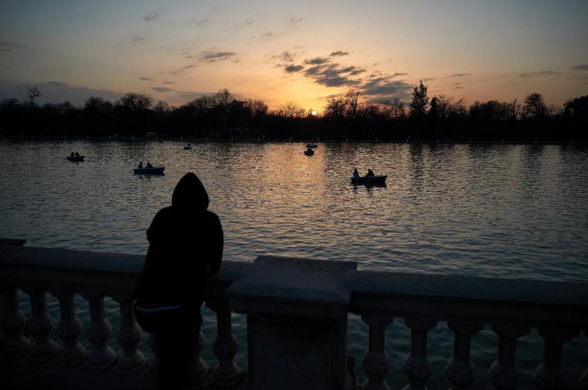 Una persona observa el atardecer en el Parque del Retiro