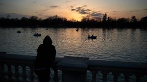 Una persona observa el atardecer en el Parque del Retiro