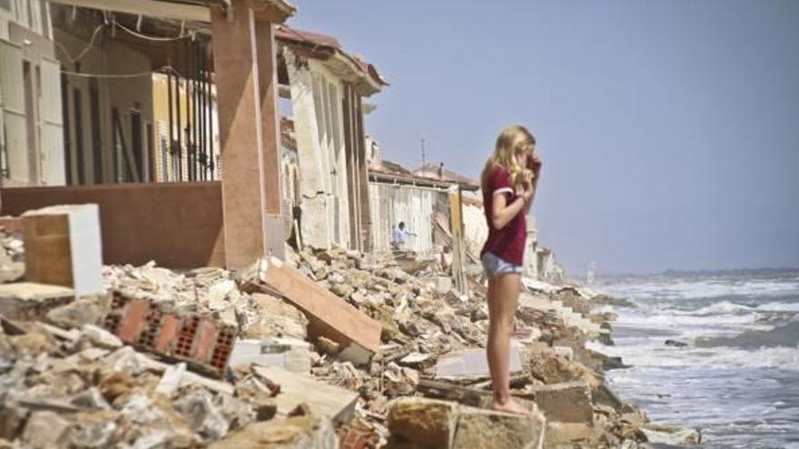 Una niña subida a los escombros amontonados junto a la playa de casas que han sido derribadas por la fuerza del mar con el paso de los años.