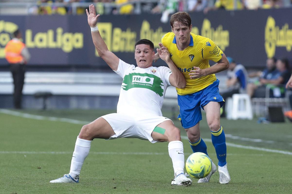 El delantero argentino del Elche CF Guido Carrillo (i) lucha por el balón con el centrocampista del Cádiz CF Álex Fernández, durante el partido de la jornada 35 de Liga en Primera División en el Estadio Nuevo Mirandilla, en Cádiz. EFE/Román Ríos.