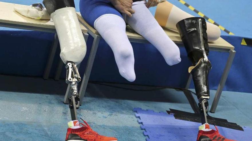 Un atleta paralímpico se prepara para competir, con sus prótesis ante él.