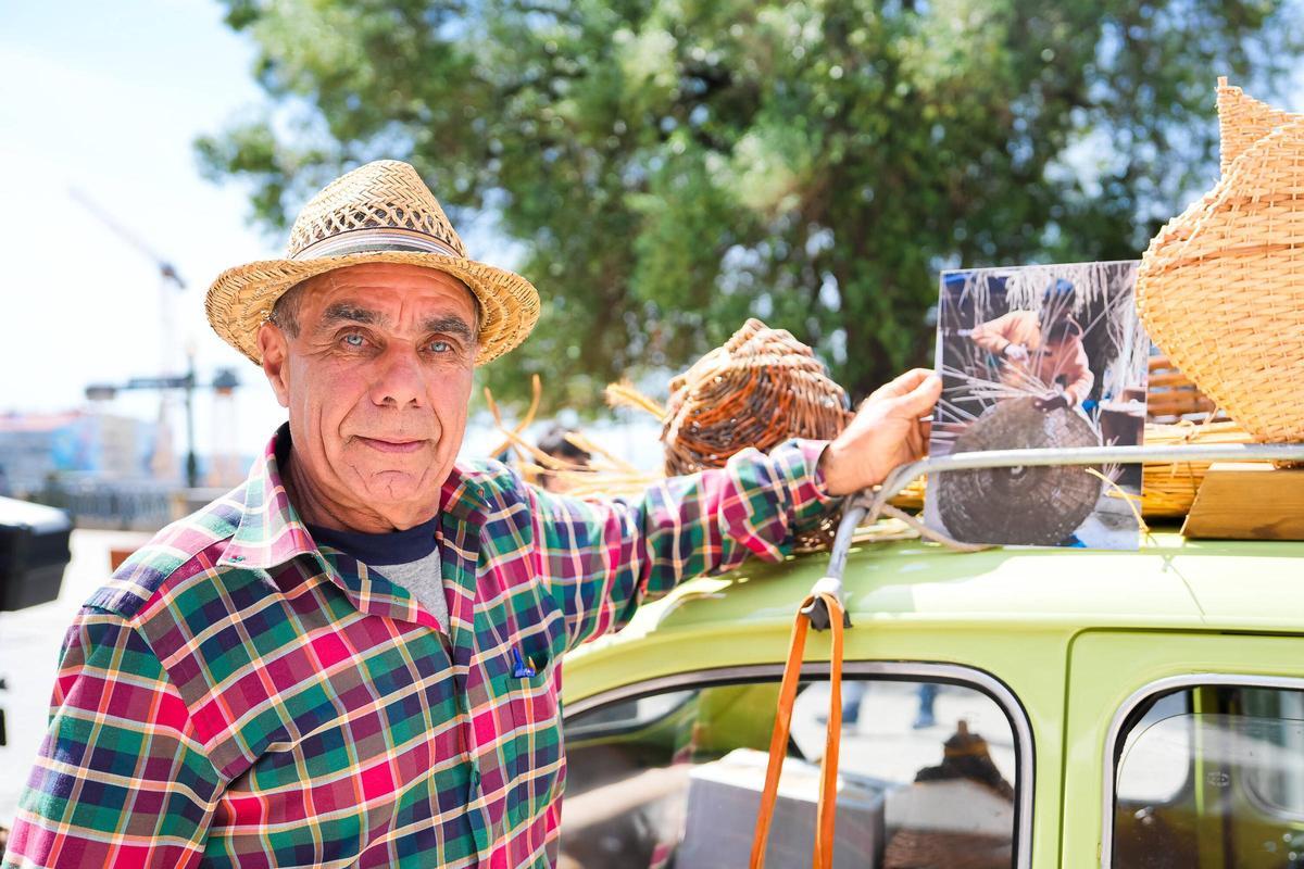 El padre de Rubén Berto Covelo sujeta una foto de su hijo encima de un coche verde donde también se sitúan piezas elaboradas por el artesano y divulgador.