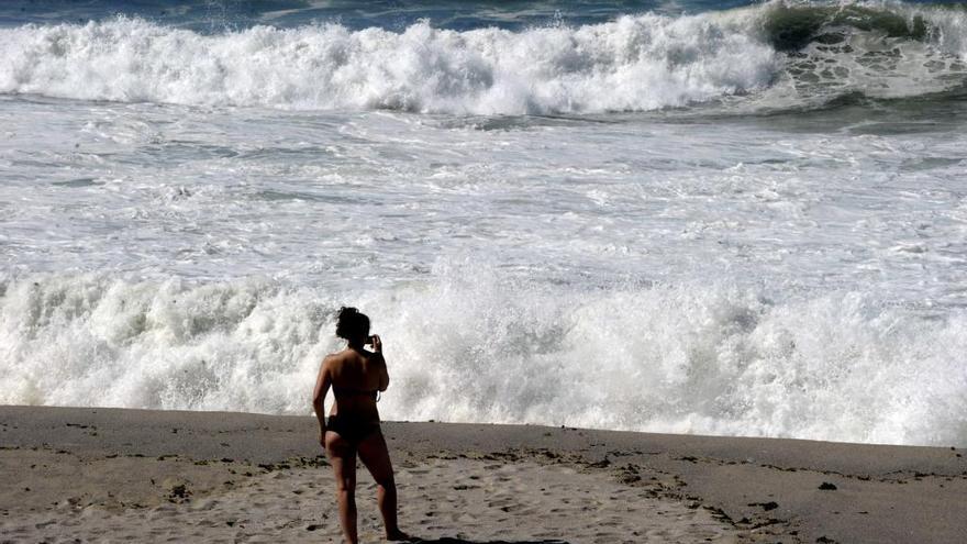 Una bañista observa el oleaje en pleamar. // V. Echave