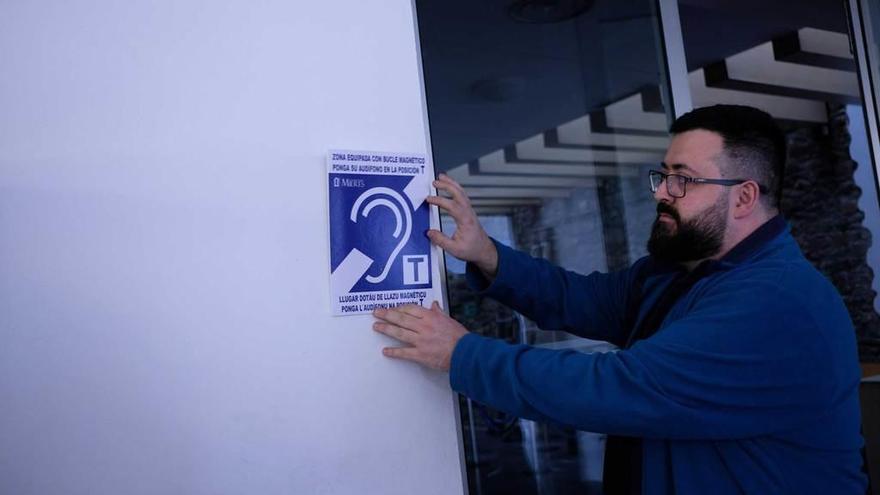 Marco Castañón, técnico de sonido de la Casa de Cultura de Mieres, coloca la señal que identifica el auditorio de la instalación como lugar con bucle magnético para personas con implantes cocleares o audífonos.