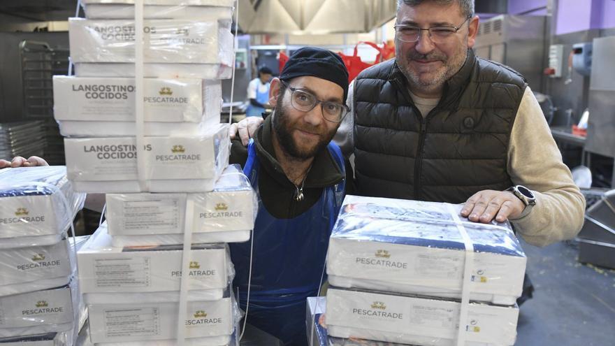 Óscar Castro, a la derecha, posa en la Cocina Económica con un compañero junto a cajas de langostinos, este martes. |  Carlos Pardellas