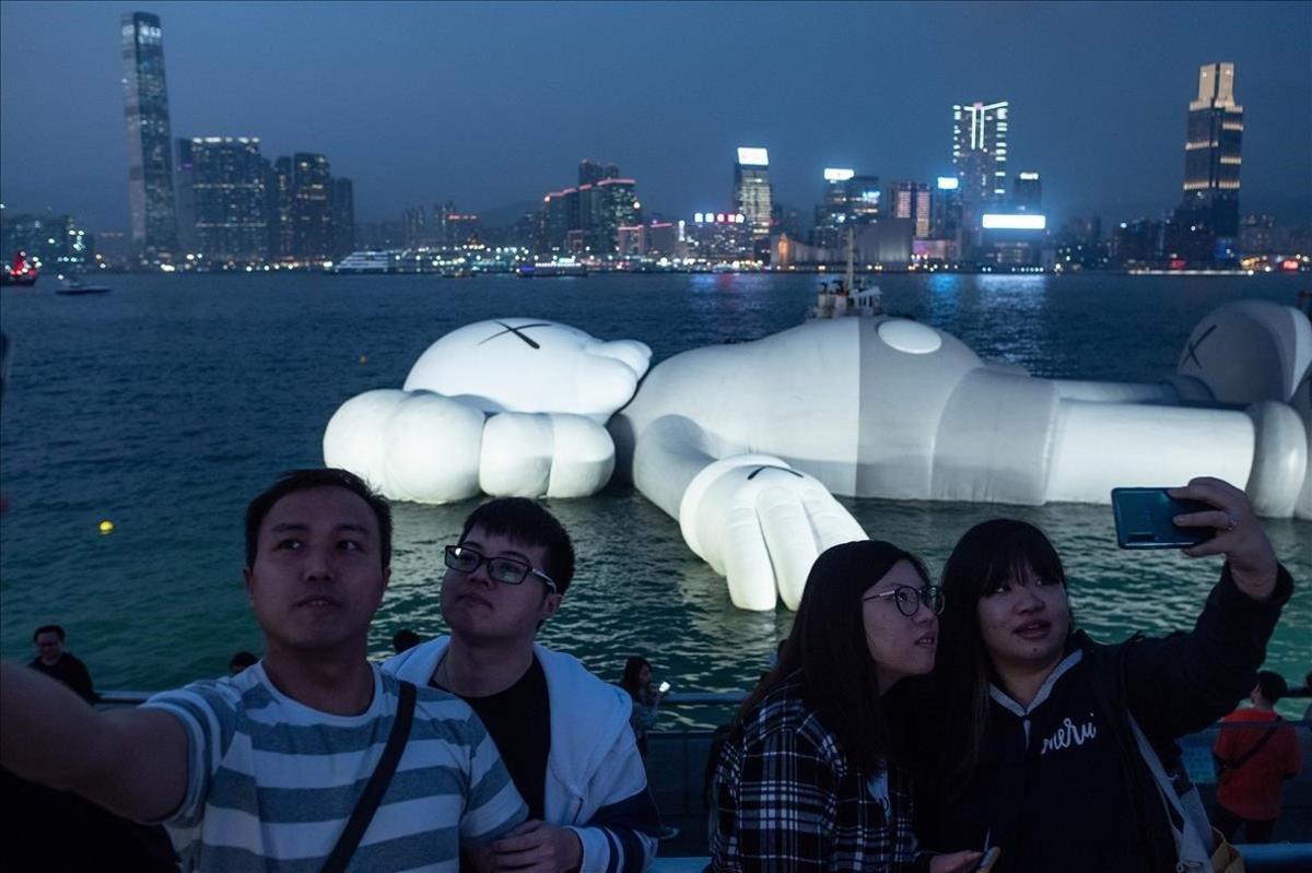 La gente se fotografia delante de una escultura de Brian Donnelly, conocido como Kaws, en el puerto Victoria de Hong Kong.