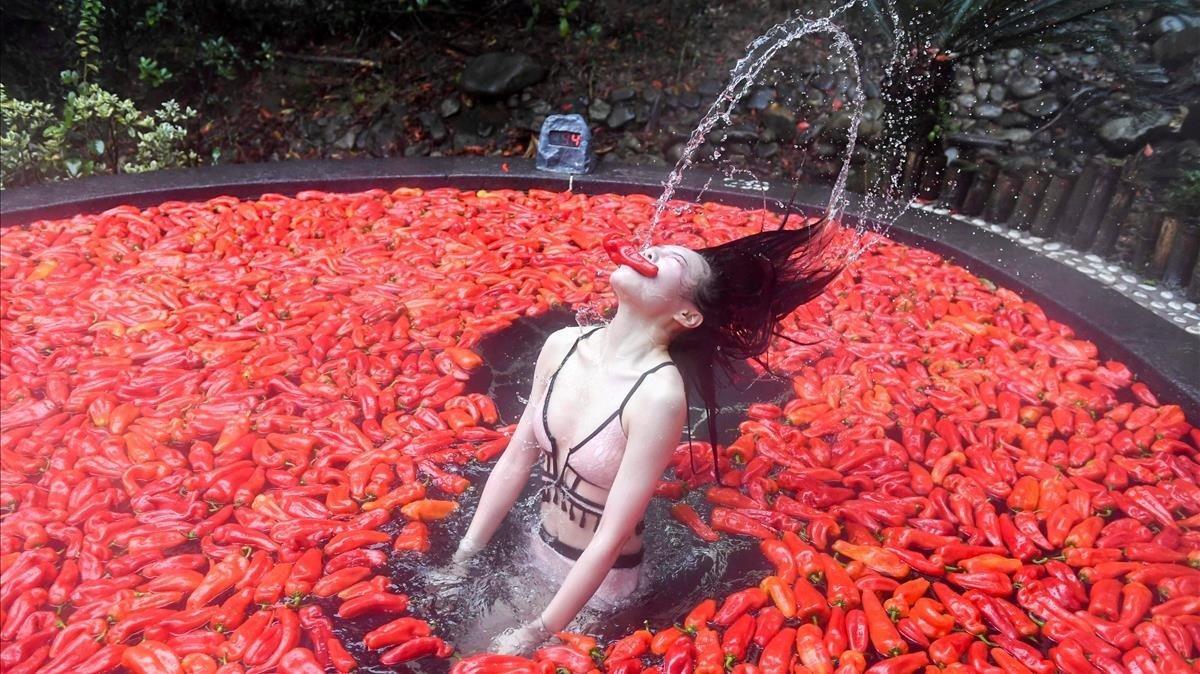 Participante rodeada de pimientos rojos picantes en una competición de comer pimientos, en China.