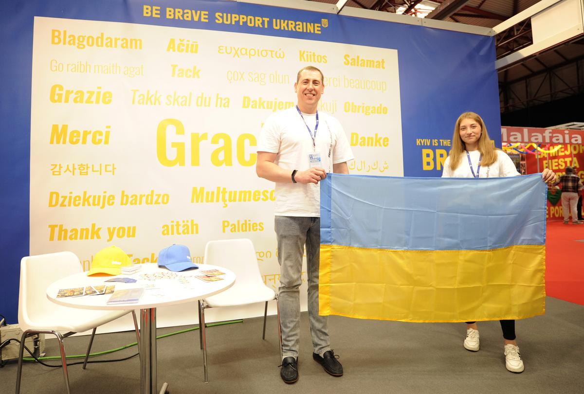 Los responsables del stand de Ucrania muestran la bandera de su país-