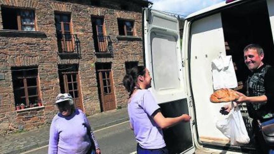 Adriano Díez, panadero ambulante, vende una pieza de pan de escanda a Marta Mieres en la travesía de Illano. / ángel gonzález
