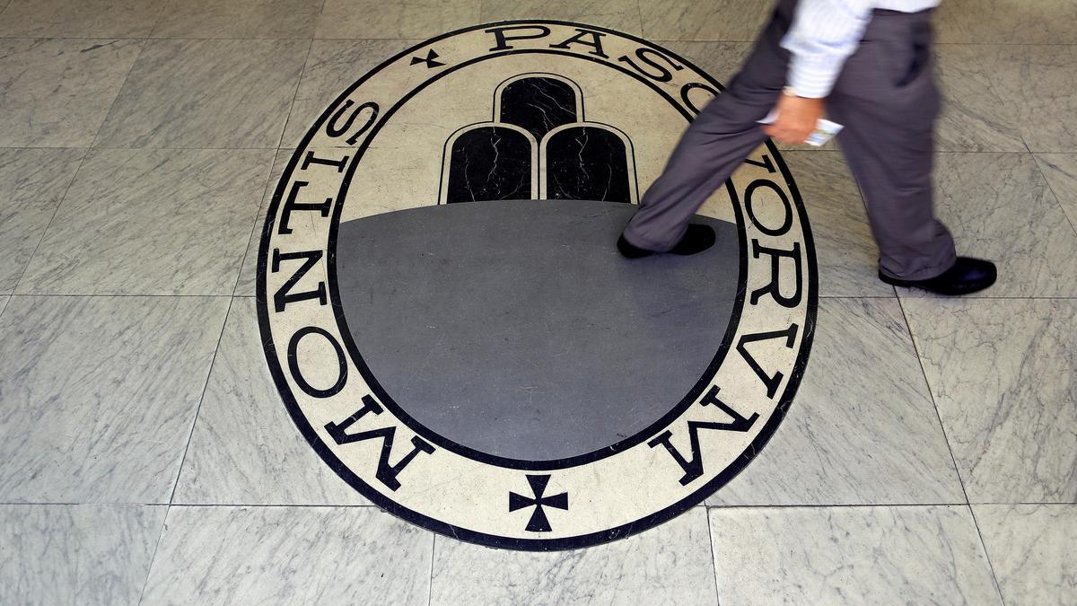 Un hombre camina sobre el logo del banco Monte Dei Paschi Di Siena en Roma.