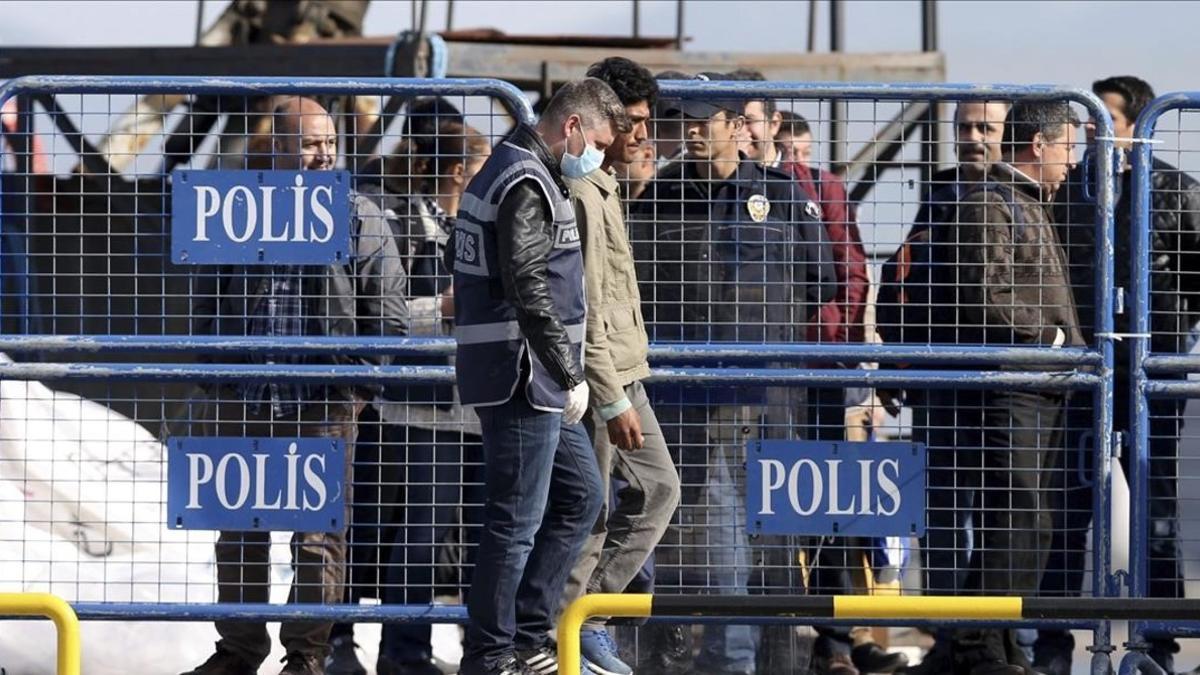 Policías escoltan a los refugiados que llegan al puerto de Dikili en Izmir, Turquía.