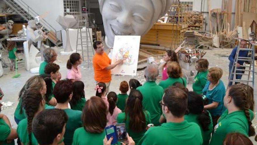 El artista Pere Baenas explica a los festeros de Carolinas Altas los detalles del monumento que plantará en el distrito.