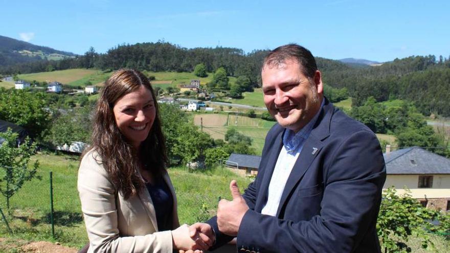 Mayra García y César Álvarez se dan la mano en la escuela de Abres, con Ría de Abres al fondo.