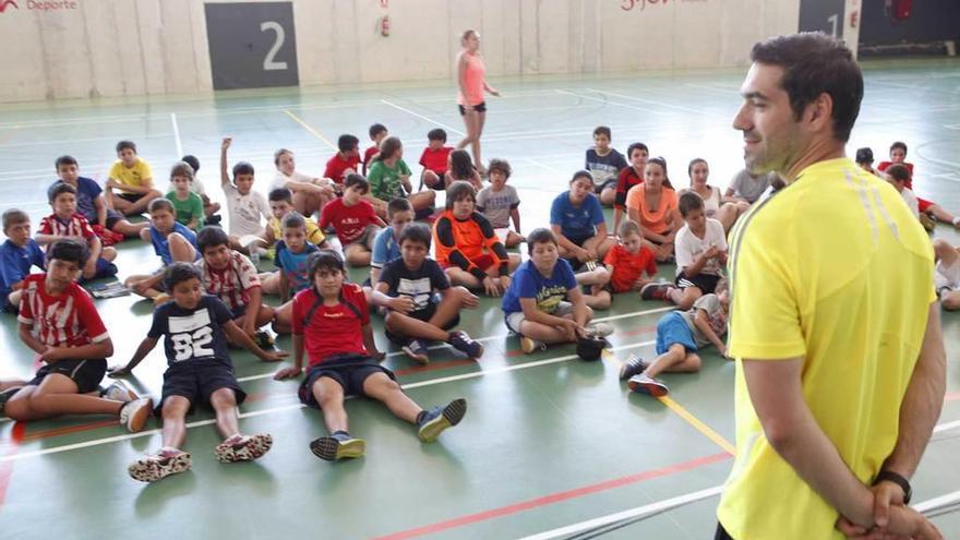 Niños participantes en un campus de balonmano, atentos al jugador Víctor Álvarez.