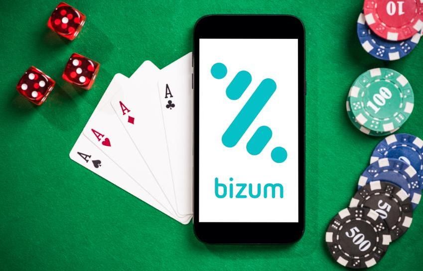 Cartas, dados y fichas de casino con Bizum junto a un teléfono móvil
