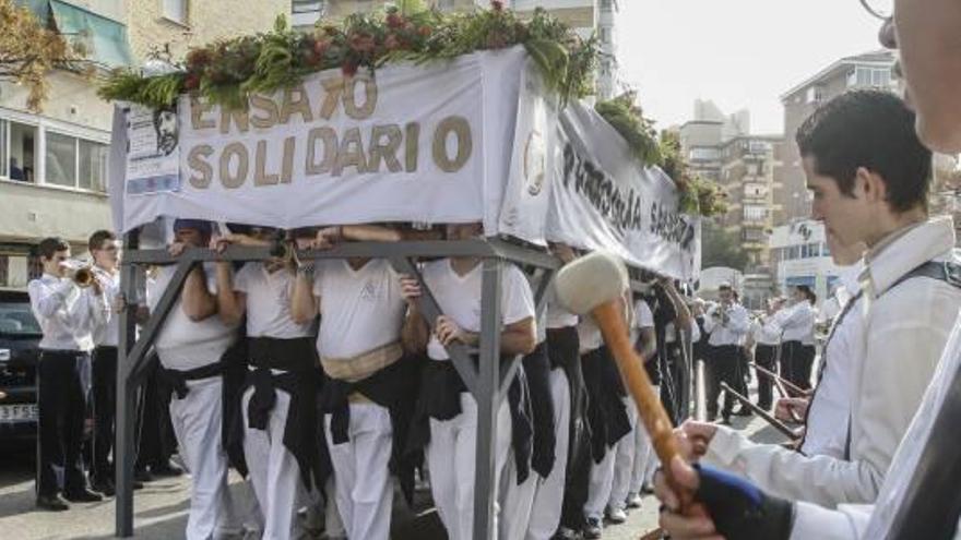 Varios costaleros caminan con la parihuela del paso del Santísimo Cristo de las Penas.