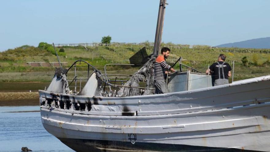 Dos hombres revisan los daños en el barco siniestrado, ayer al mediodía. |   // NOÉ PARGA