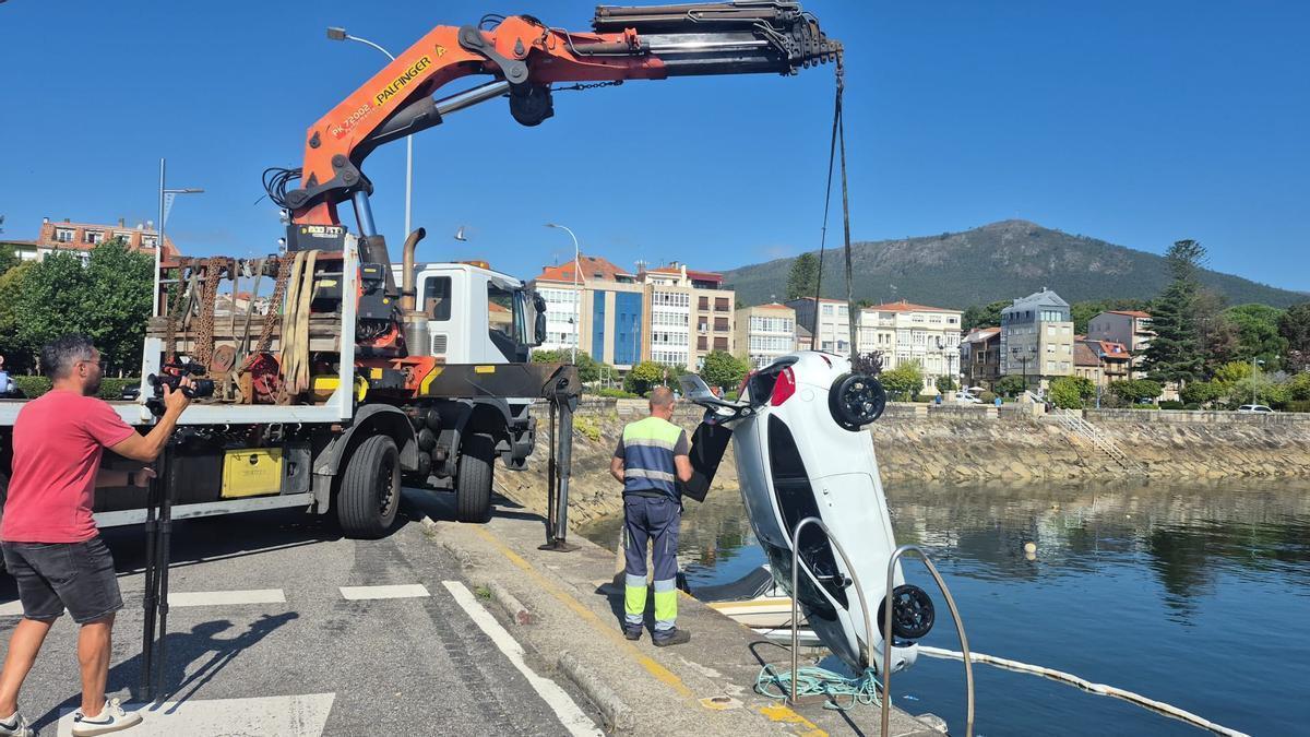 Una grúa extrae el coche caído al agua en A Pobra.