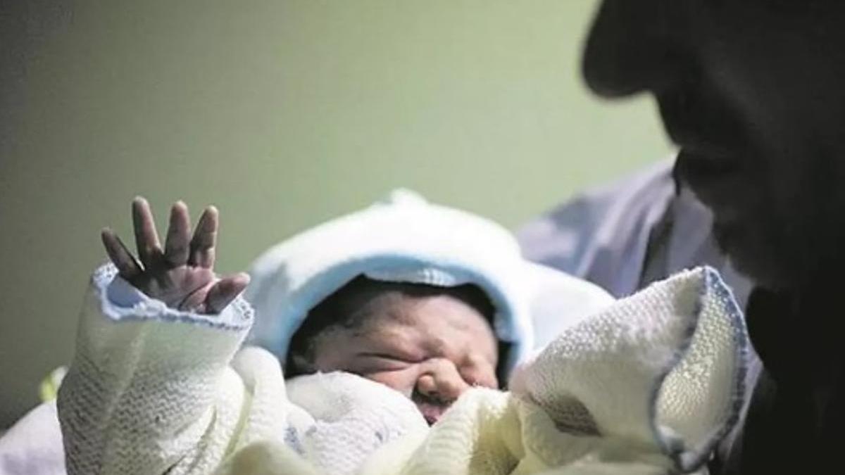 Una persona sostiene en brazos a un bebé recién nacido.