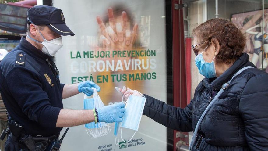 Un policia reparte mascarillas entre la población.