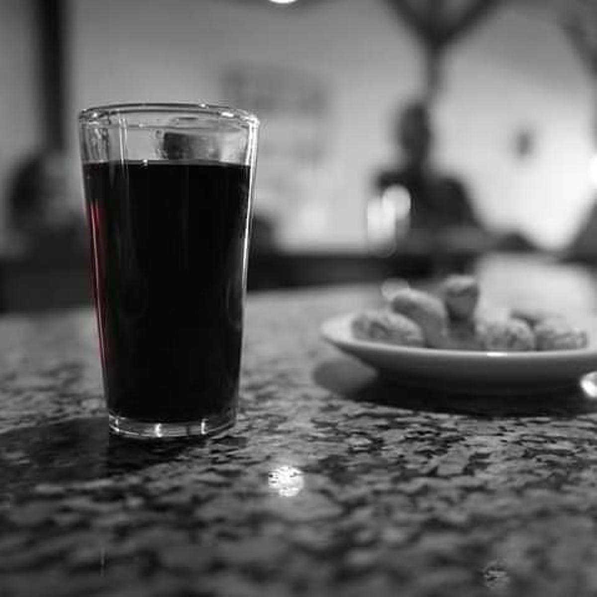 Un vaso de vino de tinto y unos cacahuetes.