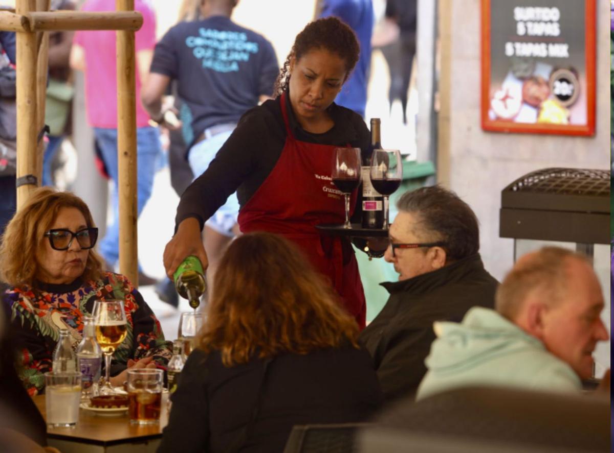 Una camarera atiende a unos clientes en un establecimiento de hostelería en Málaga. | ÁLEX ZEA