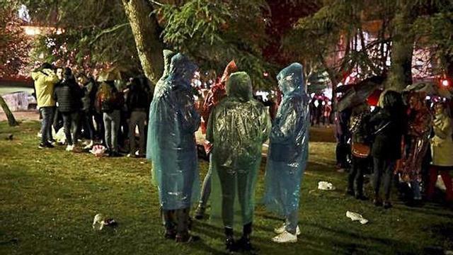 Jóvenes, de botellón, con el chubasquero puesto.
