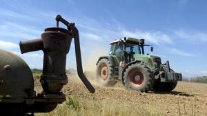 Un tractor trabaja junto a una bomba de agua en los campos de arroz.