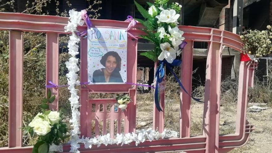 Flores junto a una valla con la foto de la mujer fallecida.