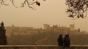 Dos personas observan la Alhambra de Granada desde el Mirador de San Nicolás durante el episodio de calima del pasado mes de marzo, uno de los más intensos registrados en las últimas décadas.