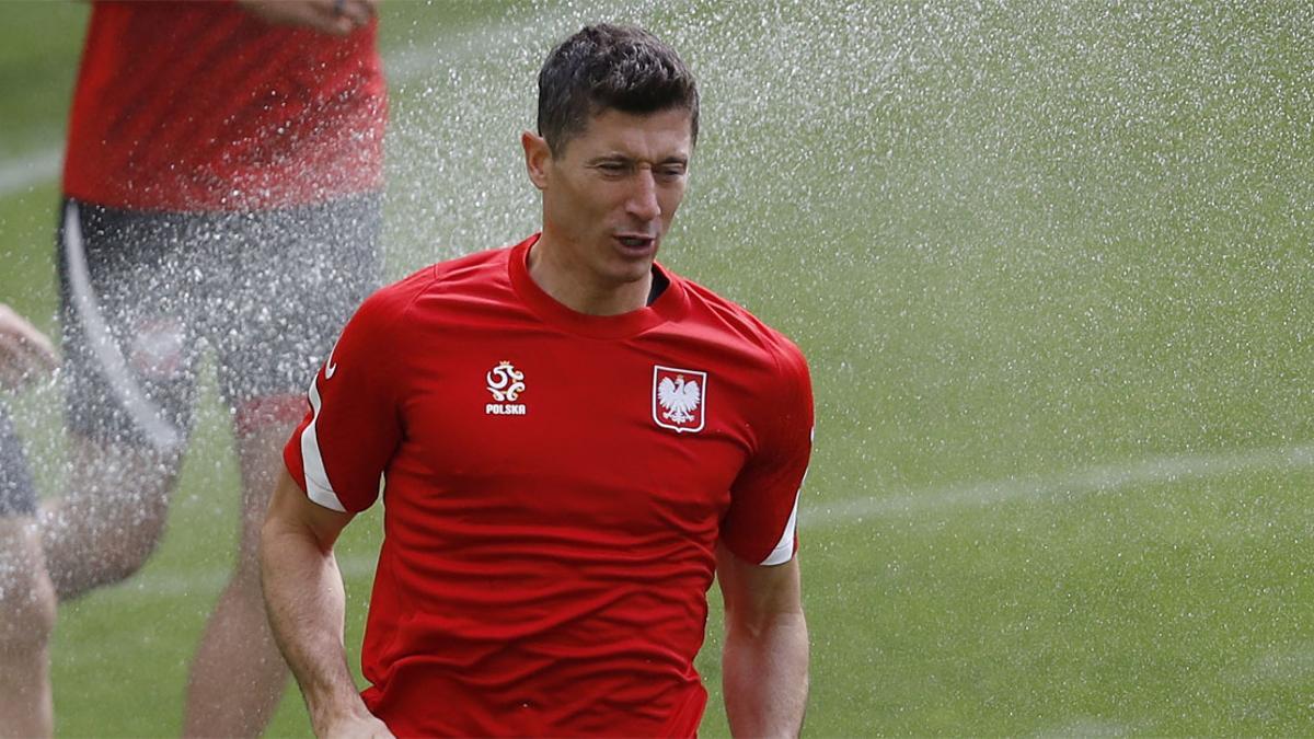 Robert Lewandowski pasa por delante de una boca de riego durante el entrenamiento previo al estreno en la Eurocopa