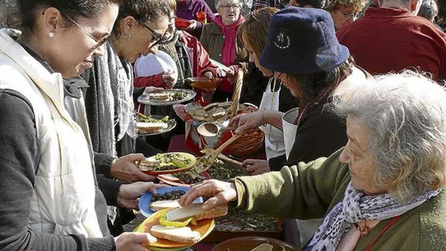 Voluntarios repartiendo la típica comida de la fiesta de es Quarteró: arenques con verduras.