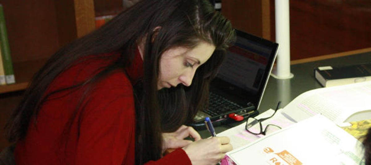 Una mujer estudia en una biblioteca.