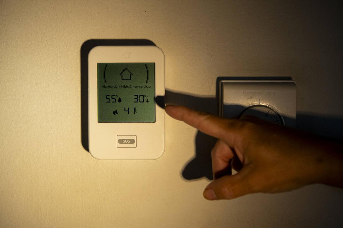 Una vecina señala los 30 grados que marca el termostato de su casa en el bloque de vivienda pública de la calle Tiana. Barcelona, 21 de agosto de 2026. Foto: Belén González / EP