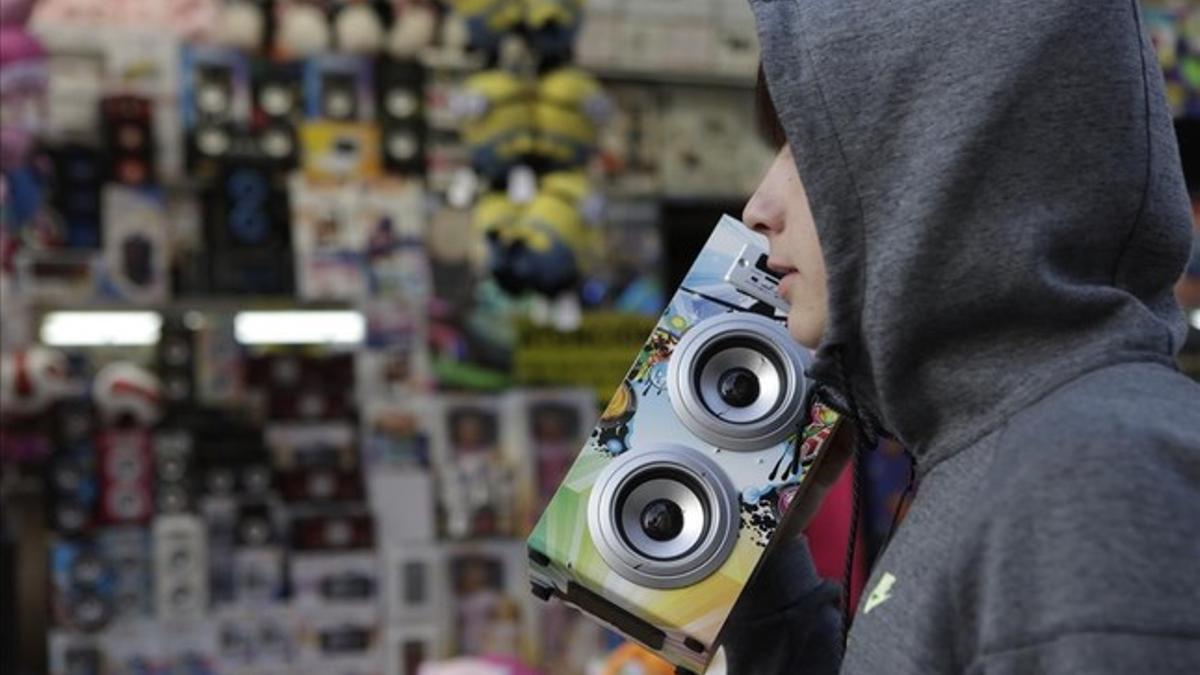 Un joven con un altavoz autoamplificado y con bluetooh, en una tómbola de una feria del barrio de Sant Antoni, la semana pasada.