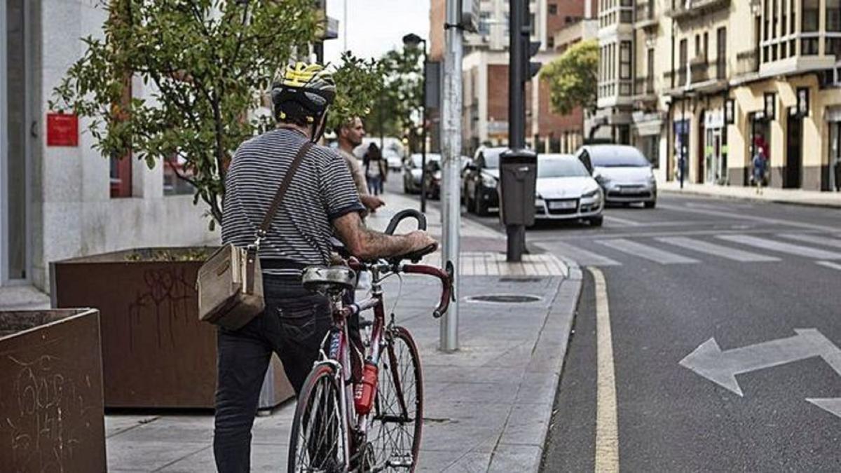 Un hombre camina por la acera con una bicicleta | EMILIO FRAILE