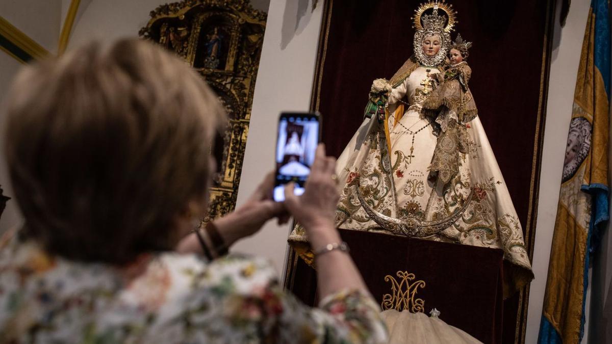 Una mujer fotografía a la Virgen del Yermo con el Niño restaurados, en la iglesia de San Lázaro . | Emilio Fraile