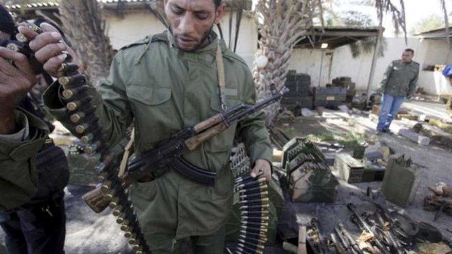 Un soldado libio pasado a los opositores al régimen de Gadafi revisa la munición.