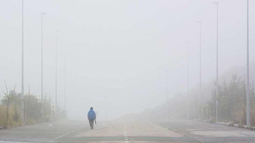 Un hombre caminando ayer, entre la niebla, en el polígono de Vío.