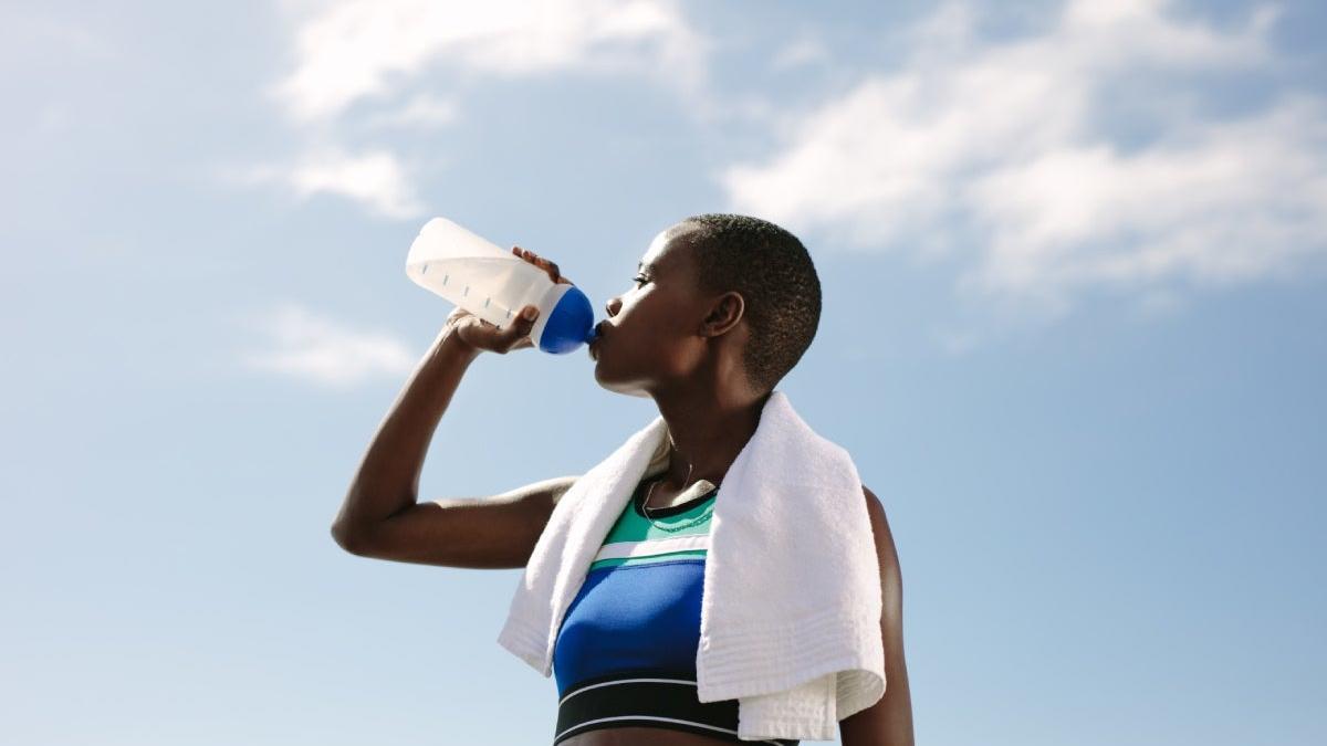 Mujer bebiendo agua mientras hace deporte