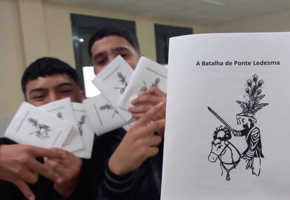 Dous alumnos amosan exemplares do libro de cordel. |
