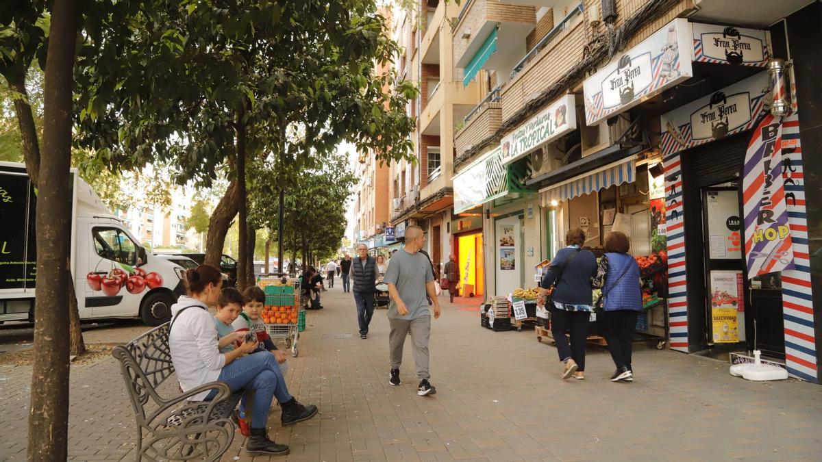 Varias personas pasan por una calle comercial del barrio de La Viñuela.