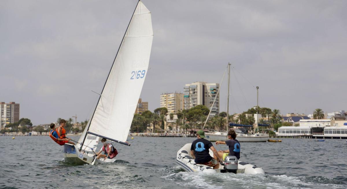 Dos monitores de la escuela de vela dan indicaciones a unos alumnos durante una clase.