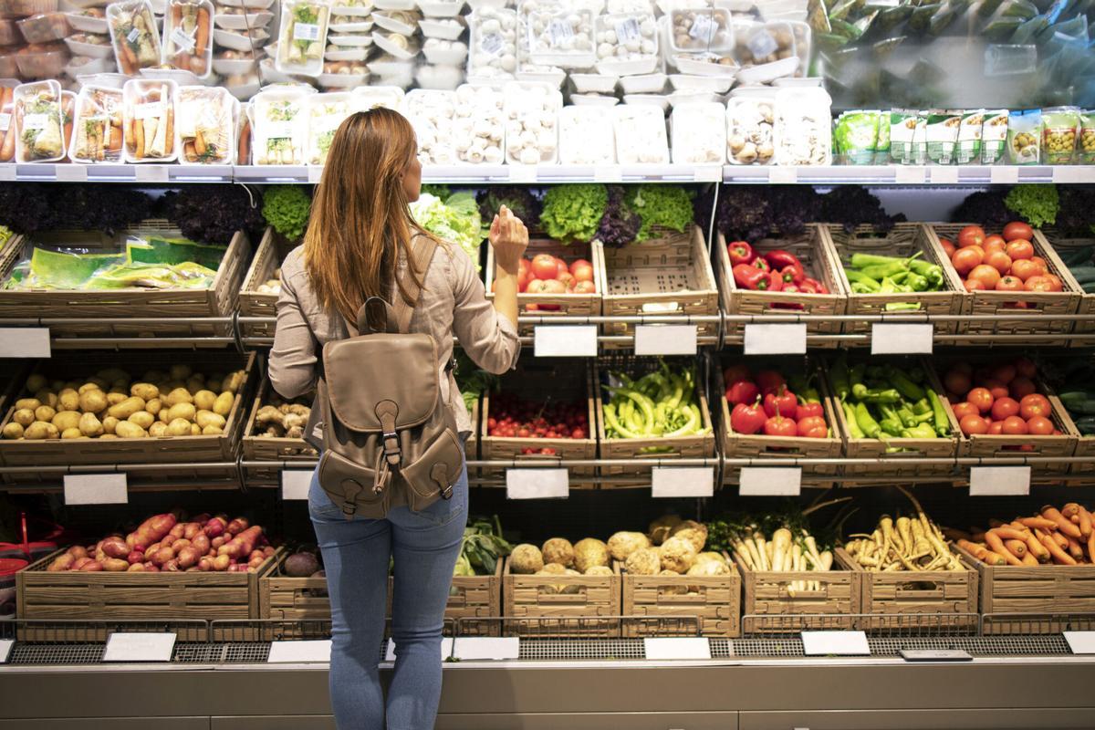 Good looking woman standing in front of vegetable shelves choosing what to buy