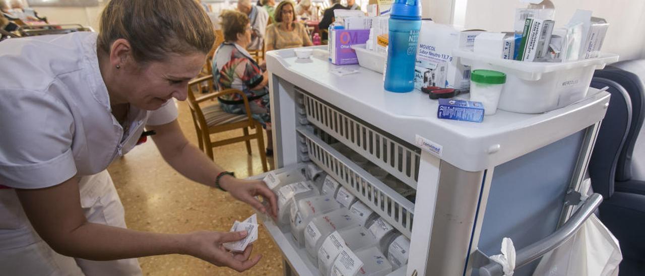 Una enfermera recoge los medicamentos para dispensarlos a los residentes a la hora de la comida.