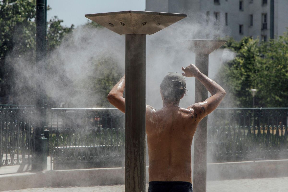 Un parisino usa un rociador de agua para refrescarse en uno de los parques de la capital francesa.
