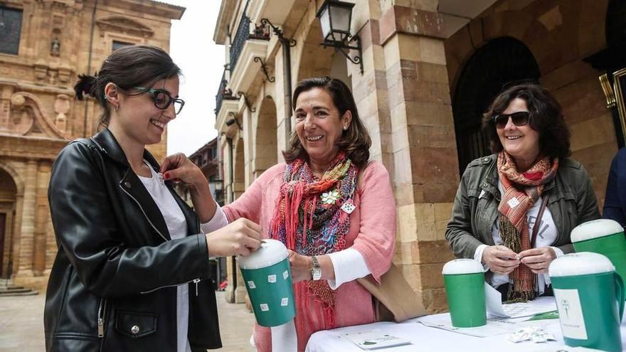 Mónica Figaredo coloca la pegatina de la asociación a una joven; tras ella, en la mesa, Lola González de Mesa.